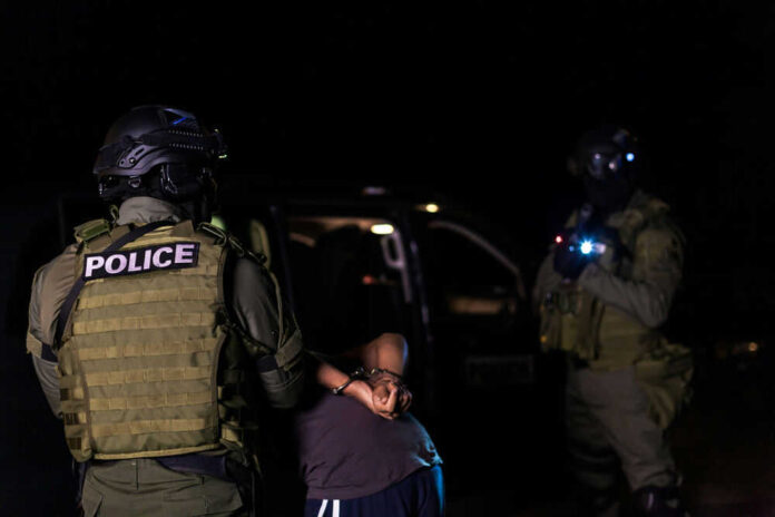 1786607321 Police officers arresting a person at night