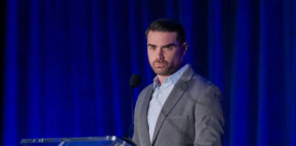 Man speaking at a podium with blue curtains