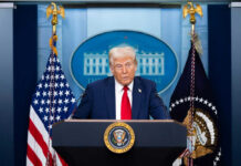 Trump’s AI Power Grab: States Fight Back Man speaking at podium with flags in background