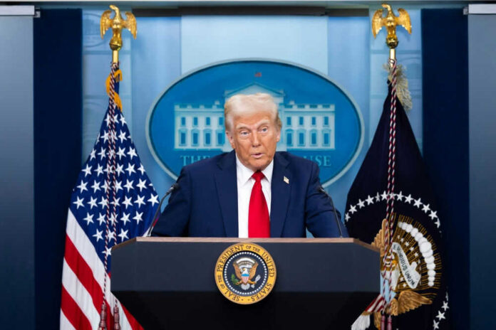 2591233783 Man speaking at podium with flags in background