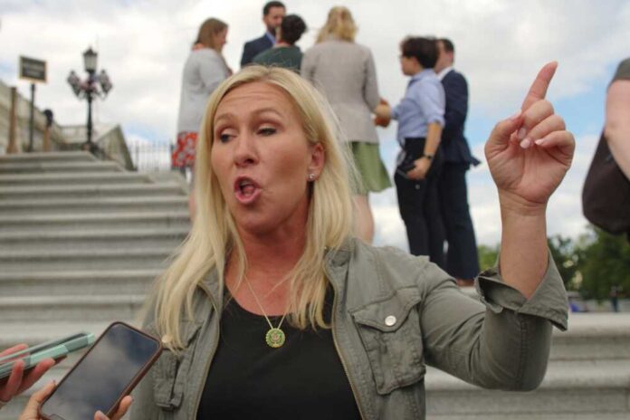 A woman passionately speaking outdoors, surrounded by people and media.