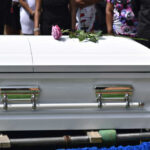 White casket with pink rose at funeral service