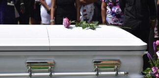 White casket with pink rose at funeral service