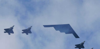Five military aircraft flying in formation under clouds