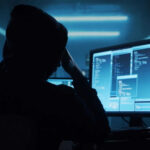 Person in a hoodie using multiple computer screens