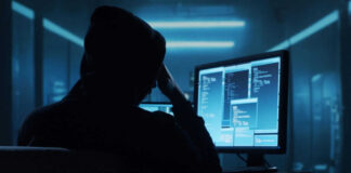 Person in a hoodie using multiple computer screens