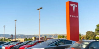 Tesla cars parked near red Tesla sign