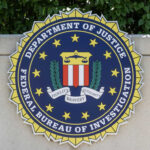 DOJ “Strike Force” Sparks Outrage FBI seal on stone wall with foliage background