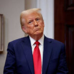 Man in suit with red tie looking contemplative