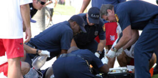 Emergency responders assisting person on grass lawn