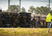 Overturned truck with people standing nearby outdoors
