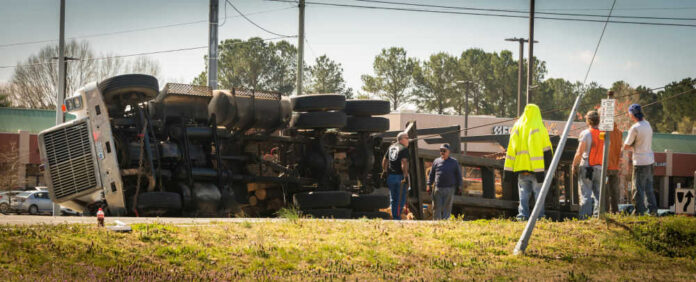 Overturned truck with people standing nearby outdoors