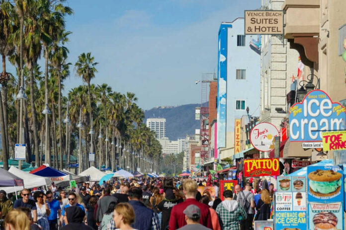 Crowded Venice Beach boardwalk with palm trees and shops