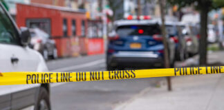 Police tape blocking street with parked cars