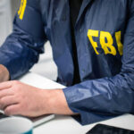 FBI Foils New Year Terror Plot—Details Missing! Person in FBI jacket using a laptop