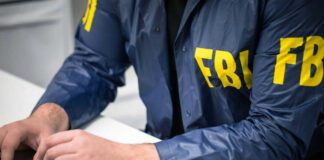 Person in FBI jacket using a laptop