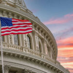 American flag and Capitol building against colorful sky