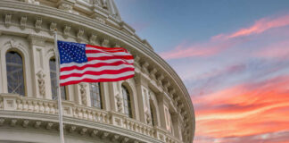 American flag and Capitol building against colorful sky