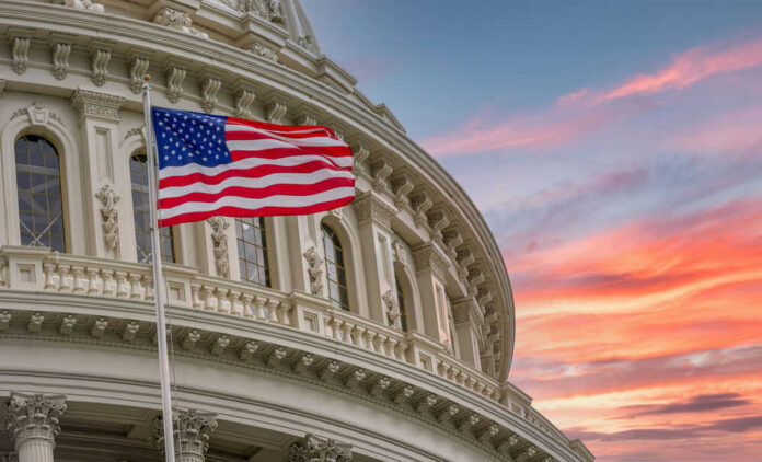 American flag and Capitol building against colorful sky